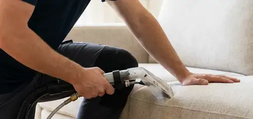 Professional upholstery cleaner deep-cleaning a fabric sofa with a handheld extraction tool, Lakewood, CO.
